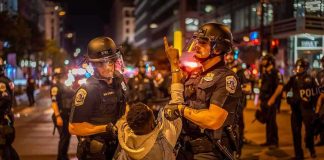 Bus Stop Street Chaos – 15-Year-Old Did WHAT? Police officers detain a protester at night on a city street