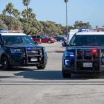 Shoplift Call, Baby Dead – Then Resignations Two police SUVs with lights on in a coastal parking lot