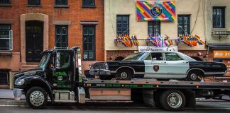 Tow truck carrying vintage sheriff car on city street