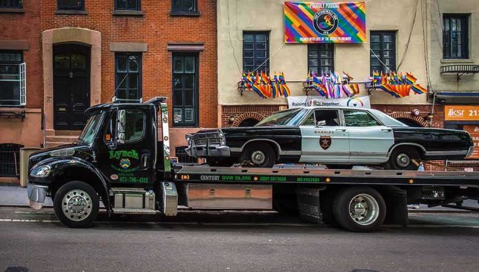 Tow truck carrying vintage sheriff car on city street
