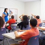 Schools Hid Transitions – Policy OVERTURNED Teacher leading classroom discussion with students raising hands