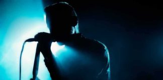 Shock Move: Free Palestine Hits Gillette Singer silhouette holding a microphone on a dark stage