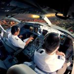 Flight Plunge Triggers Chilling Questions Pilots in an airplane cockpit during city approach at sunset