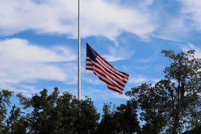 American flag at half-staff against a blue sky