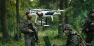 Helicopter Denied, Drone Pulls Off The Impossible quadcopter drone hovering near soldiers in a forest