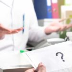 Envelope Scare Freezes Offices Nationwide Doctor gesturing during consultation with patient holding paper with question mark