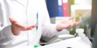 Doctor gesturing during consultation with patient holding paper with question mark